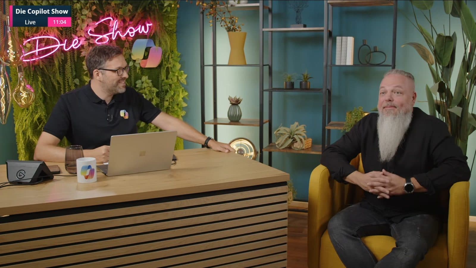 Alexander Eggers am Moderationstisch im Gespräch mit Gast Florian Sandmann-Reetz im gelben Sessel, Folge 2