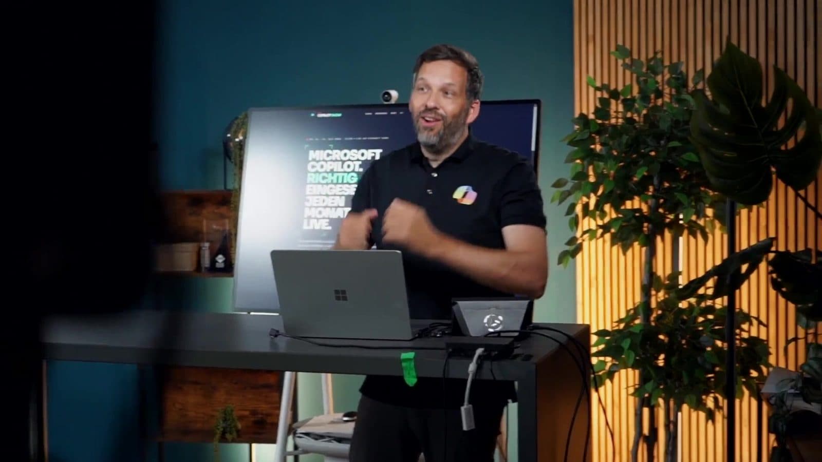 Alexander Eggers am Demo-Tisch vor einem großen Bildschirm im Studio